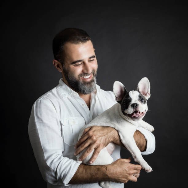 Man with his dog on black background, studio shot. French bulldog puppy | Top Shelf Trailers | Top Shelf Trailers Man with a dog